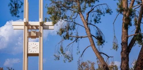 the pitzer clock tower with a pine tree in the foreground