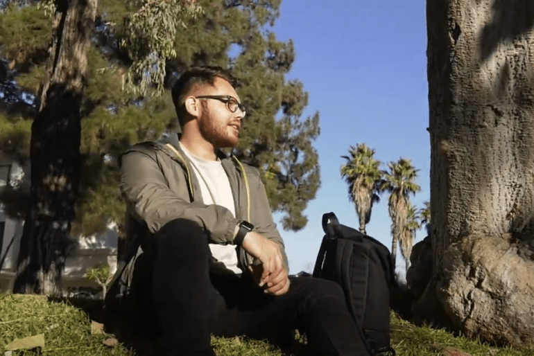 Carlos Perrett sits on the Pitzer Mounds while discussing his study abroad experience. 